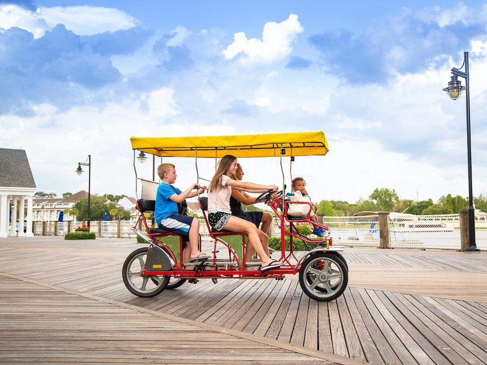 Junge Familie in einem Tretmobil auf einer Promenade in Florida (Foto © Brocreative/Shutterstock.com)
